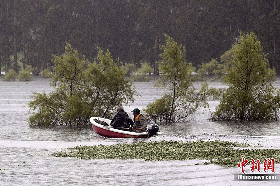 图为5月16日，一名男子和救援人员在哥伦比亚波哥大附近地区乘舟渡过被洪水淹没的农场。