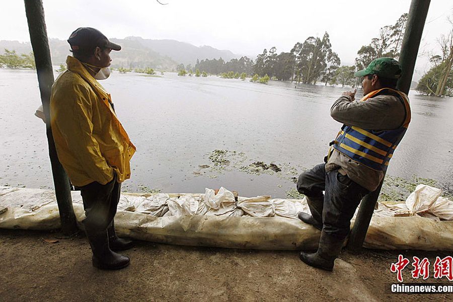 图为5月16日，在哥伦比亚波哥大附近地区，一名男子和救援人员眺望被洪水淹没的农场。