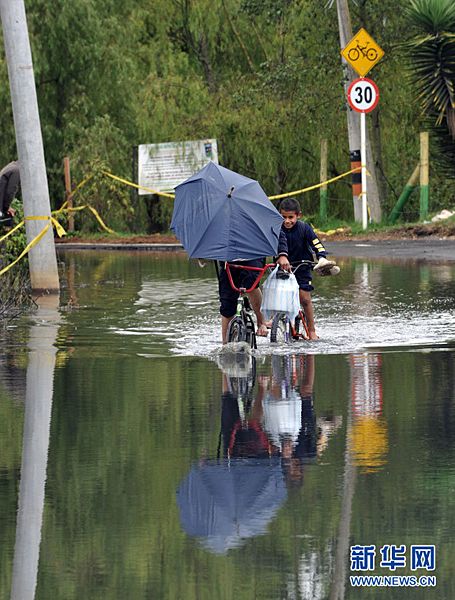 图为5月16日，孩子们在哥伦比亚波哥大附近骑车经过被洪水淹没的道路。