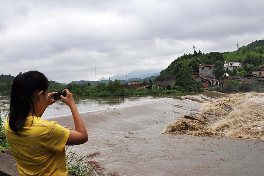 6月6日，江西德兴市，暴雨致洎水河水位上涨，部分农田被淹没。图为市民用手机拍摄水位暴涨的洎水河。胡敦煌/CFP