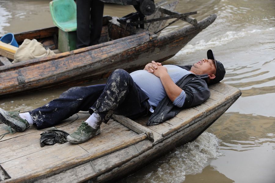 5月24日，一位无鱼可打的渔民在船上酣然入睡。 新华社记者 郝同前 摄