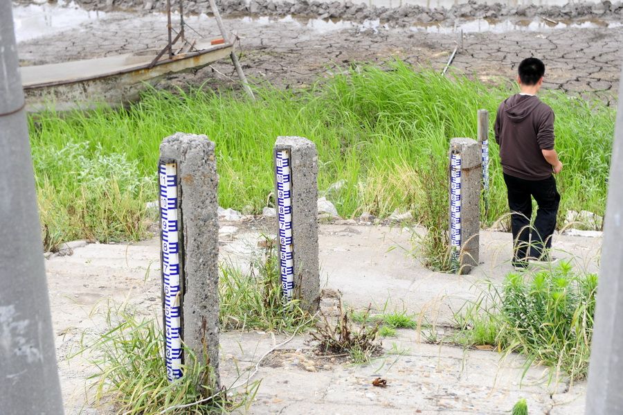 5月24日，一位行人从洪湖岸边裸露在外的水位标尺边走过。 新华社记者 郝同前 摄
