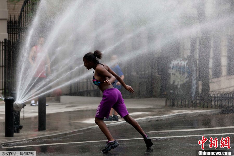 当地时间6月9日，美国纽约曼哈顿岛，一名女孩迎向消防龙头喷出的水雾。