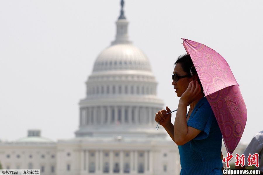 当地时间6月9日，美国华盛顿国家广场，一名妇女打伞遮阳。