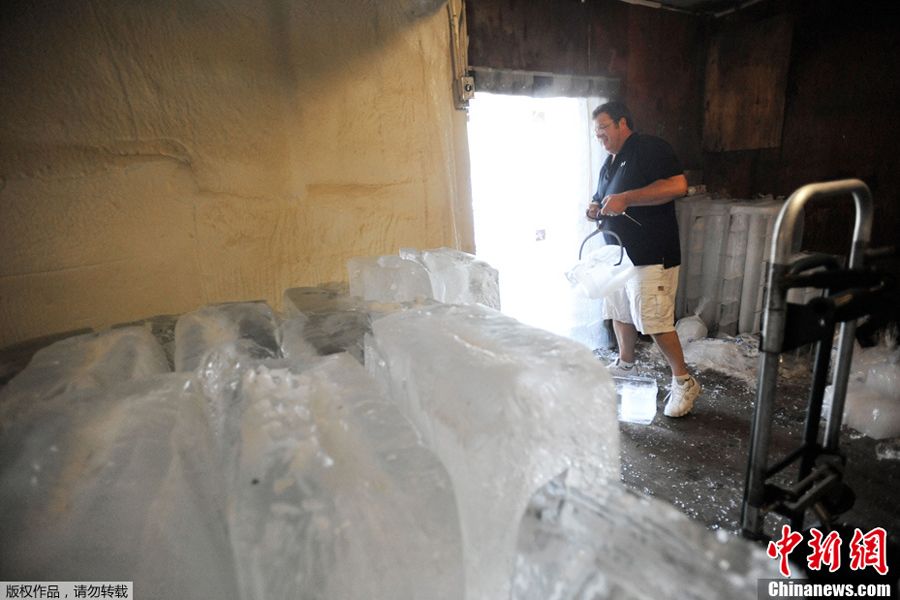 当地时间6月9日，美国巴尔的摩，一名冰场营业者将冰块从冷冻库搬出。