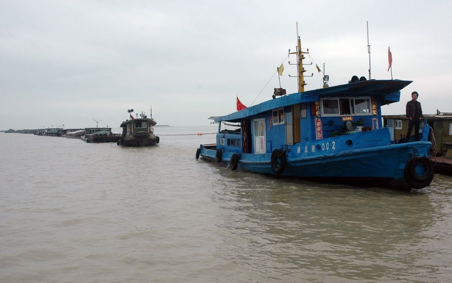 6月21日，在江苏洪泽湖南线航道内，一艘轮船（右）拖带船队前进。