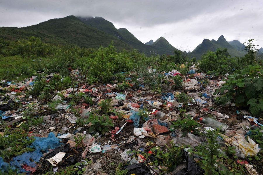 在广西阳朔县兴坪镇西塘黄花坪垃圾填埋处理场，简单处理的垃圾在青山绿草间格外扎眼（6月15日摄）。姚古镇位于广西昭平县境内，发祥于宋朝开宝年间，距今有近千年的历史，保存有300多幢明清古建筑，因风景优美成为众多影视剧的拍摄取景地。由于缺乏有效的垃圾处理设施，古镇大量土地被垃圾侵占，污水横流，甚至已经威胁到下游城镇的饮水安全。