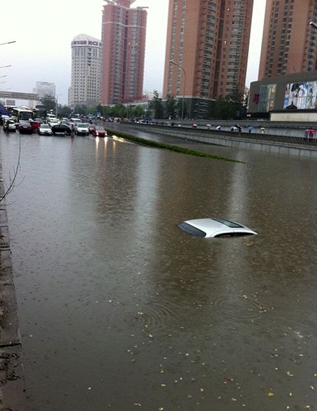 6月23日下午16时20许，北京大雨倾盆，部分地区降雨量将达50毫米以上。气象预报显示，此次降雨成为北京入汛以来最大降雨。大量路段已经瘫痪。图为6月23日，在北京西三环莲花桥附近，一辆汽车被积水淹没