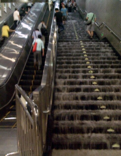 6月23日，在北京地铁4号线陶然亭站内，人们在被雨水冲刷的台阶上行走。 