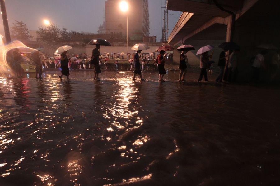 6月23日，市民在北京市莲花桥下冒雨前行。