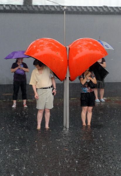 6月23日，北京，行人在电话亭下避雨。