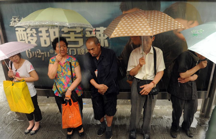 6月23日，北京，行人在广告栏下避雨。
