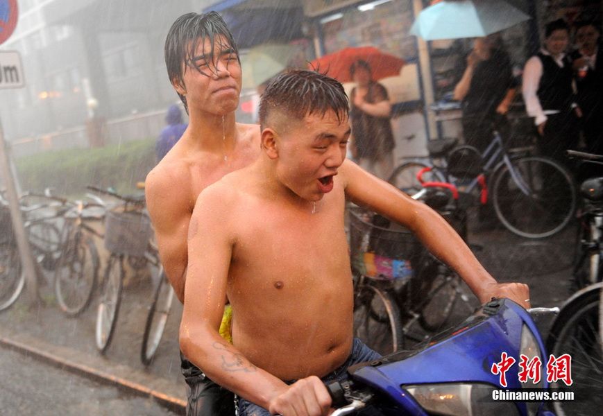 6月23日，北京，两名男子冒雨前行。