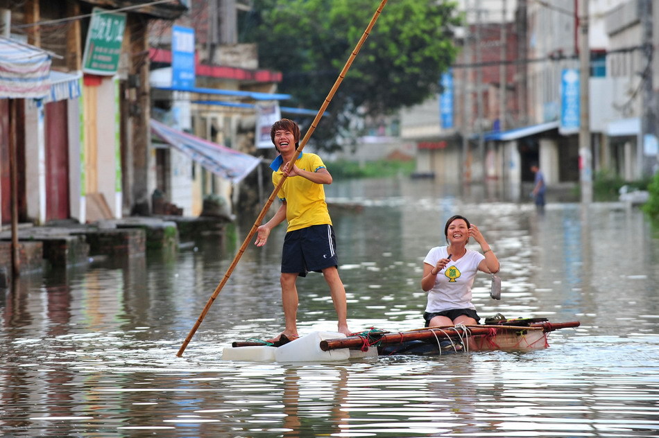 居民在积水成河的街道上撑竹筏行进