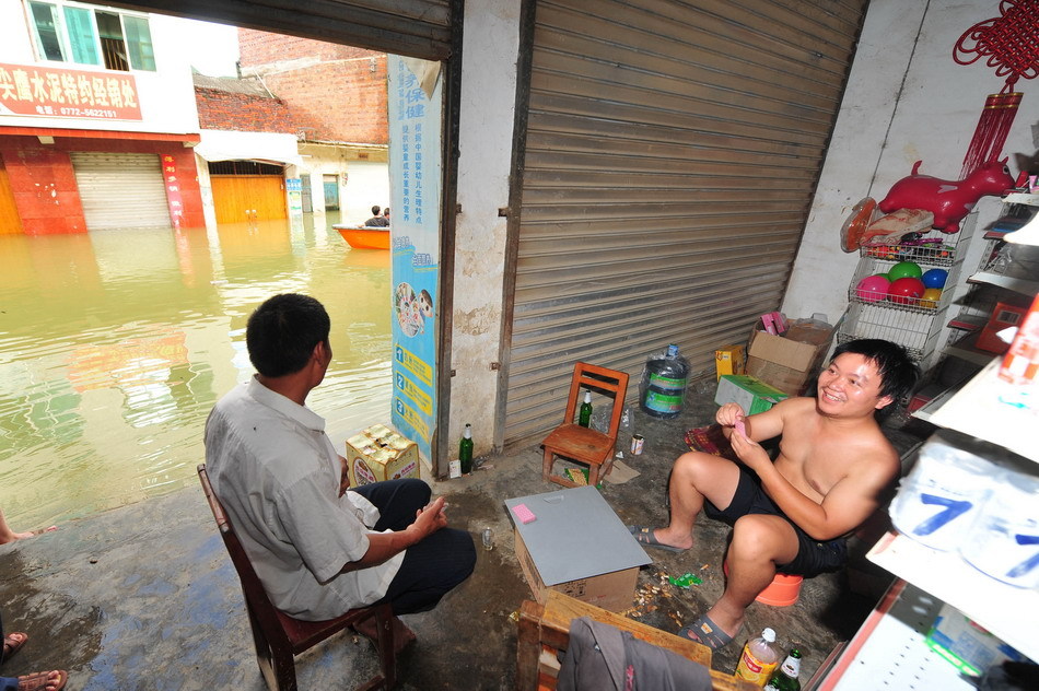 居民在积水成河的街道边打牌
