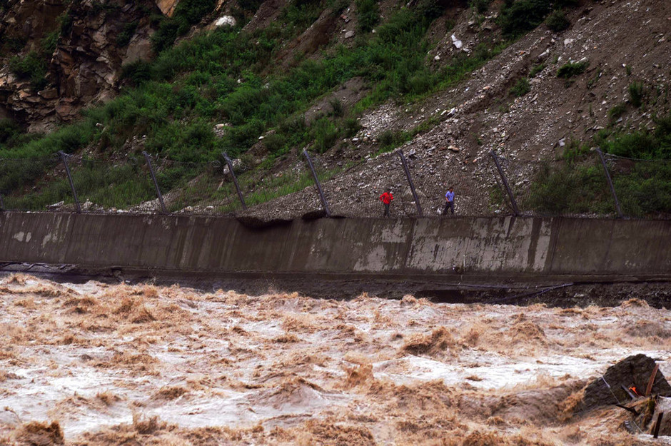 7月3日，213国道映秀至汶川段的一处塌方处，工人在抢通一条临时道路。