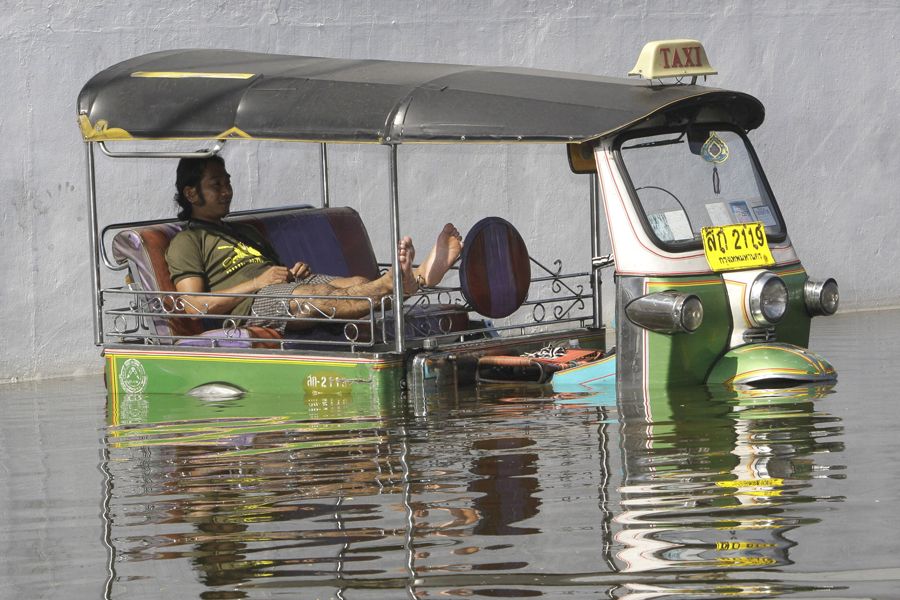 当地时间10月27日，曼谷市区一名三轮车夫在洪水中休息。