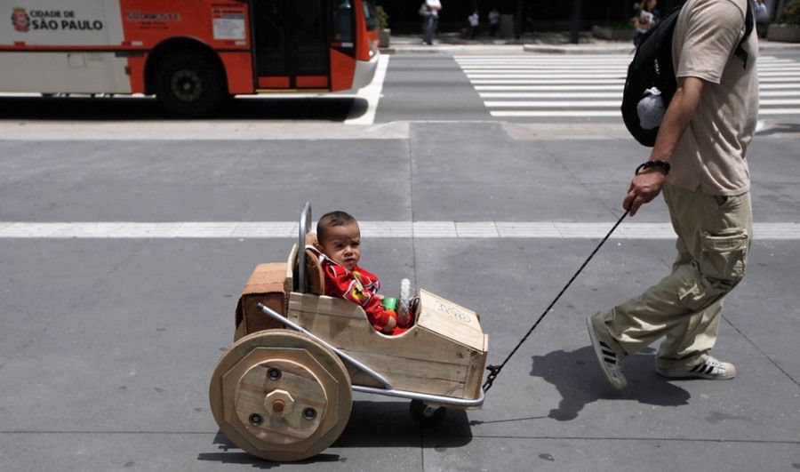 2011年10月26日，巴西圣保罗市，36岁的卡瓦罗拉着坐在婴儿车里的儿子从市中心的街道上走过。这个婴儿车是卡瓦罗用回收而来的木头制成的。