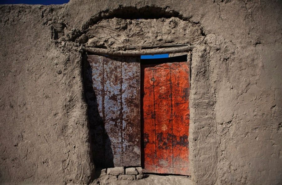2011年2月23日，阿富汗赫尔曼德省南部的一个小村庄里，一扇由废旧油桶制成的大门竖在一户人家的门前。在赫尔曼德省，很多人家的大门都是由各种废弃的材料制成的，比如油桶、集装箱铁皮、大米袋甚至几块破布。