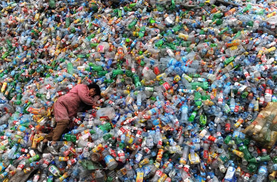 2011年11月6日，中国浙江嘉兴的一个废品回收站里，一位工人躺在成堆的塑料瓶上休息。